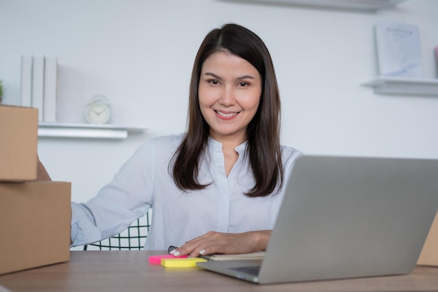 Heureuse jeune femme entrepreneure asiatique Sourire pour le succès des ventes après avoir vérifié la commande en ligne