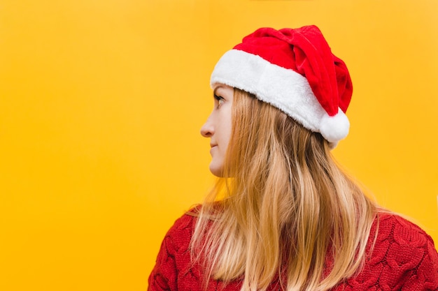 Heureuse jeune femme excitée en chapeau de père Noël sur fond jaune, place pour le texte. Notion de vacances.