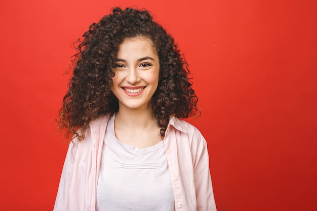 Heureuse jeune femme gaie aux cheveux bouclés regardant la caméra