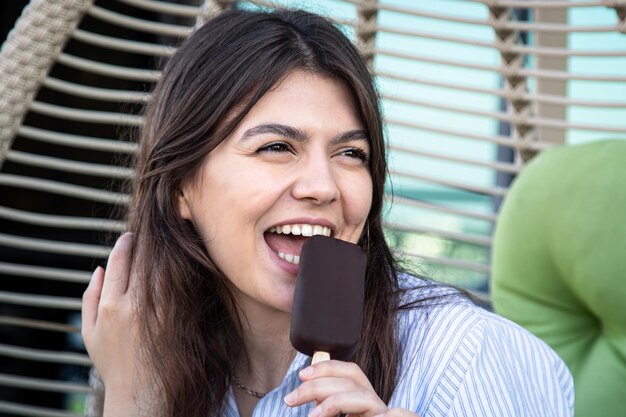 Heureuse jeune femme avec de la glace au chocolat dans un hamac