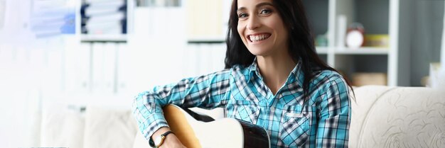 Heureuse jeune femme jouant de la guitare dans le salon à la maison