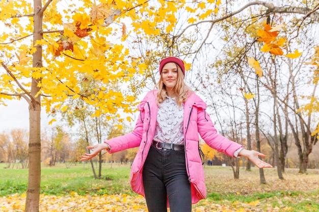 Heureuse jeune femme jouant sous les feuilles jaunes qui tombent dans le magnifique parc d'automne sur des promenades dans la nature à l'extérieur. Une adolescente jette des feuilles d'érable orange d'automne.