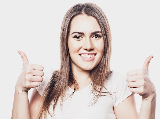 Heureuse jeune femme joyeuse montrant les pouces vers le haut isolé sur fond blanc