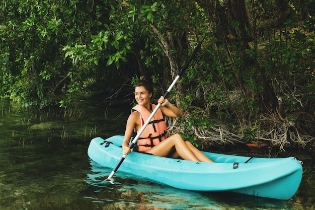 Heureuse jeune femme en kayak sur le lac