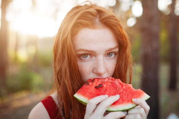 Heureuse jeune femme mangeant des pastèques sur la nature.