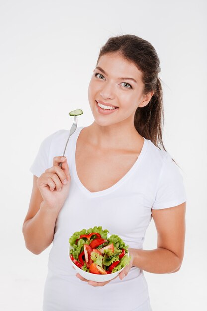 Heureuse jeune femme mangeant une salade de légumes