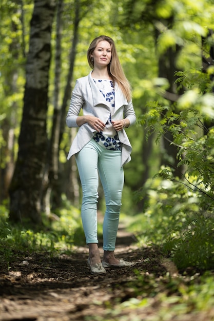 Heureuse jeune femme marchant dans le parc d'été