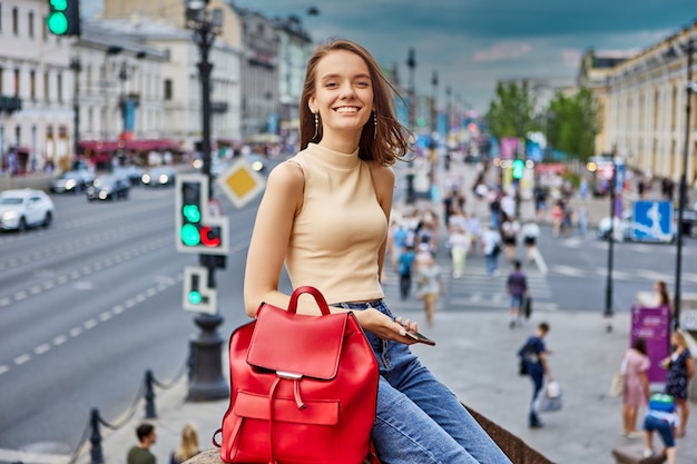 Heureuse jeune femme marche dans la rue de la ville et sourit