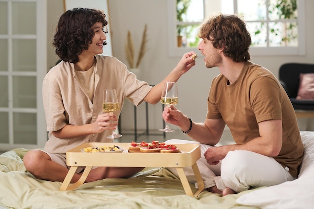 Heureuse jeune femme mettant un morceau de collation dans la bouche de son mari