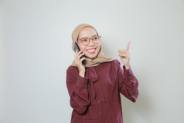 Heureuse jeune femme musulmane asiatique portant des lunettes faisant un appel avec un téléphone portable