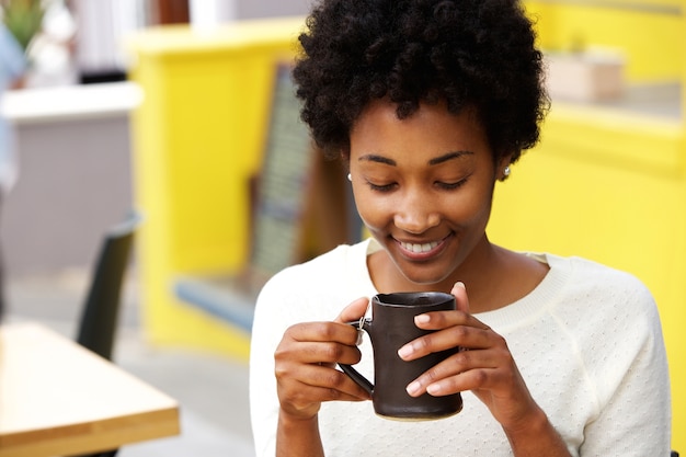 Heureuse jeune femme noire, boire du café