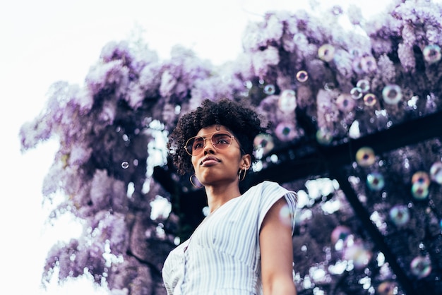 Heureuse jeune femme noire entourée de fleurs