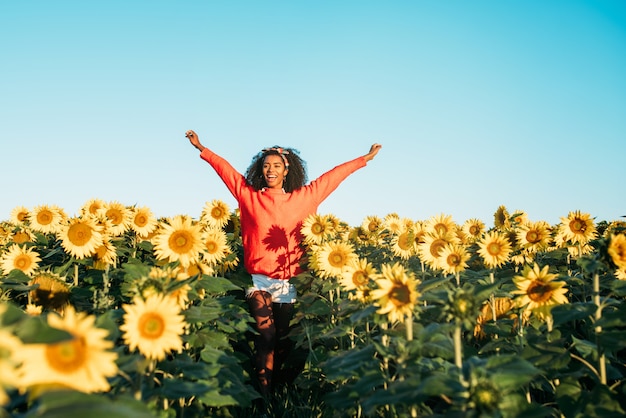 Heureuse jeune femme noire marchant dans un champ de tournesols