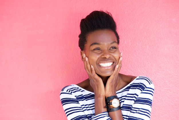 Heureuse jeune femme noire souriante avec les mains sur le visage