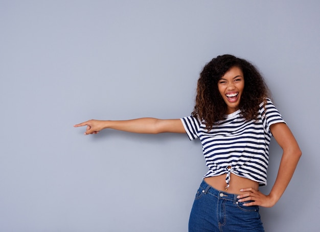 Heureuse Jeune Femme Noire Souriante Et Pointant Contre L'espace De La Copie Sur Fond Gris