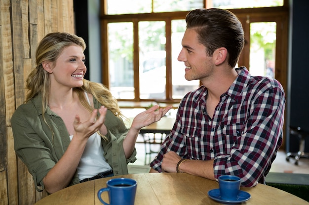 Heureuse jeune femme parlant avec l'homme à table dans un café