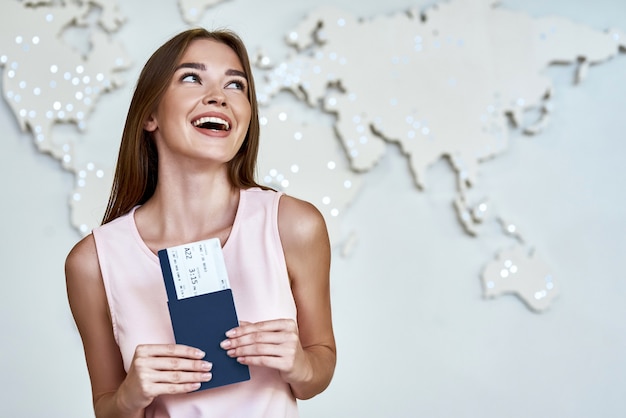 Heureuse jeune femme avec passeports et billets au bureau de l'agence de voyage