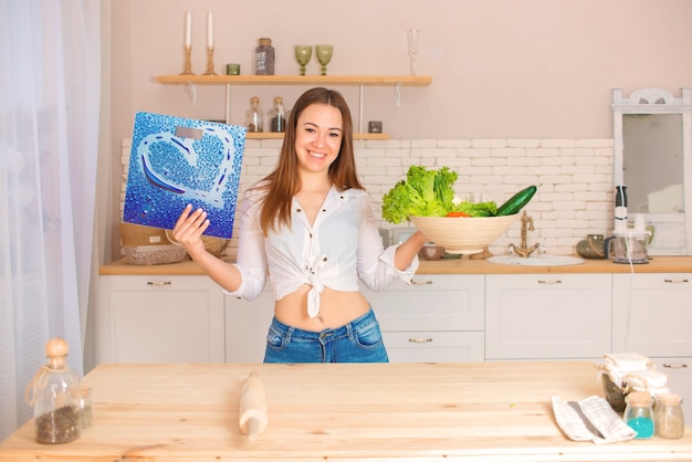 Heureuse jeune femme avec un pèse-personne dans les mains et les légumes est heureuse de perdre du poids, une alimentation saine et un régime alimentaire