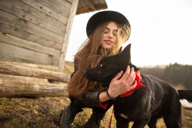 Heureuse jeune femme plaing avec son chien noir