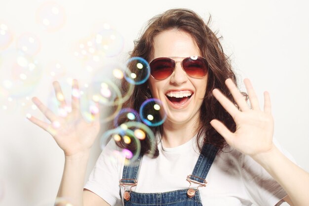 heureuse jeune femme portant des lunettes de soleil avec des bulles de savon