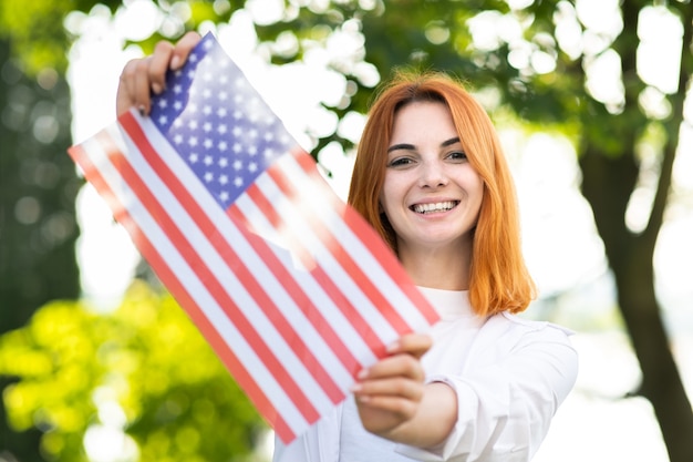 Heureuse Jeune Femme Posant Avec Le Drapeau National Des états-unis à L'extérieur Dans Le Parc D'été.