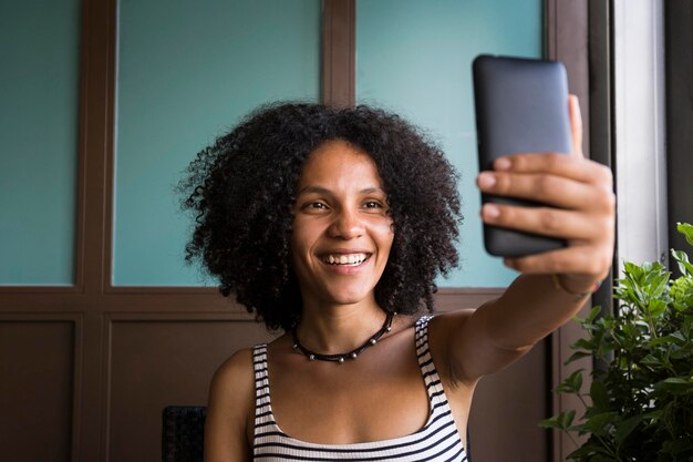 Heureuse jeune femme prenant selfie dans un café