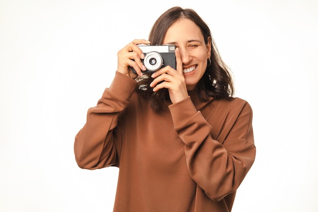 Heureuse jeune femme prend une photo avec son vieil appareil photo vintage