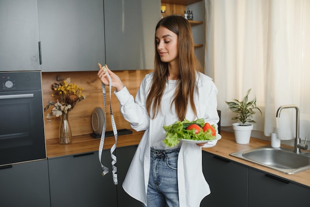 Heureuse jeune femme préparant une salade dans la cuisine Alimentation saine