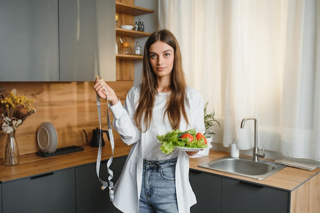 Heureuse jeune femme préparant une salade dans la cuisine Alimentation saine