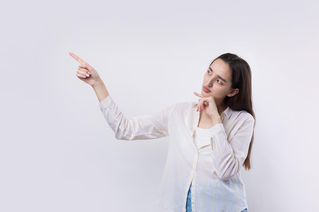 Heureuse jeune femme de race blanche dans une chemise pointant les doigts loin