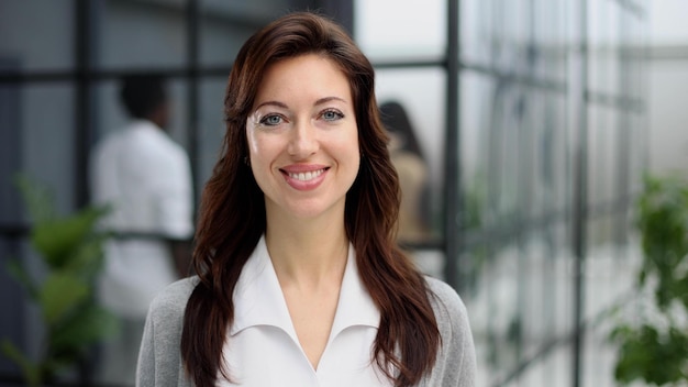 Heureuse jeune femme regardant la caméra tout en saluant un client