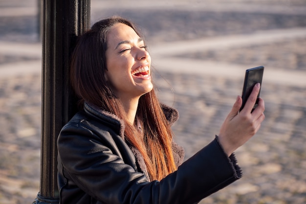 Heureuse jeune femme en riant à la recherche du téléphone