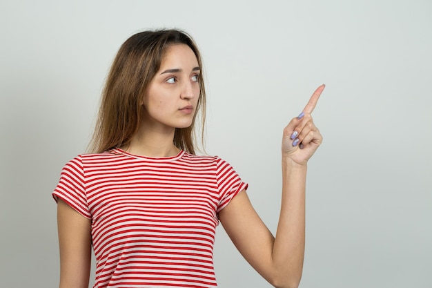 Heureuse jeune femme rousse caucasienne en chemise d'été tient sa tête La fille concernée regarde prudemment sur le côté, se sentant sous pression et perplexe