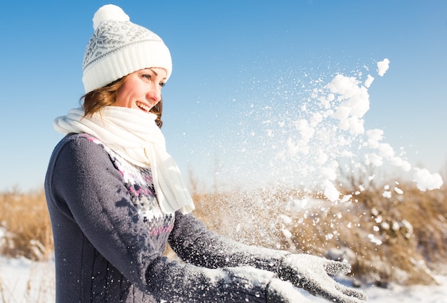 Heureuse jeune femme s'amuser et profiter de la neige fraîche à la belle journée d'hiver