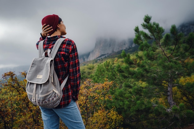 Heureuse jeune femme avec sac à dos explorant les montagnes brumeuses