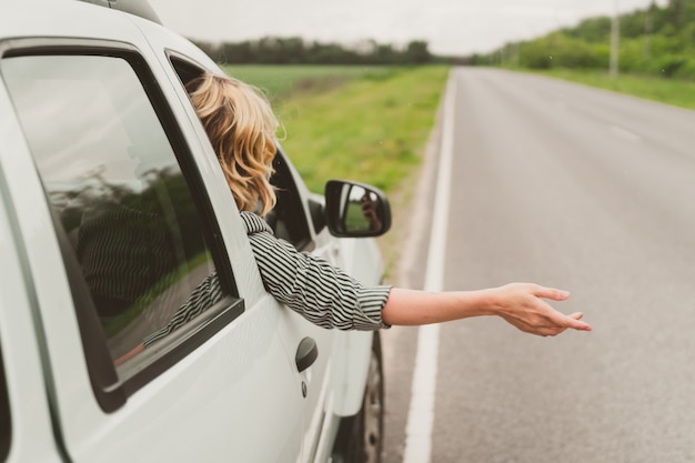 Heureuse jeune femme se déplace en voiture sur la route.