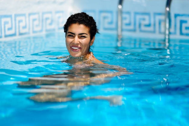 Heureuse jeune femme se détendre dans la piscine.