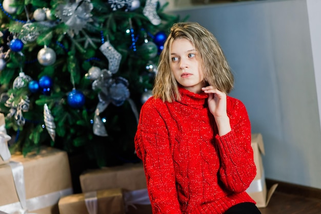 Heureuse jeune femme surprise émotionnelle par l'arbre de Noël dans un salon confortable, concept de bonheur