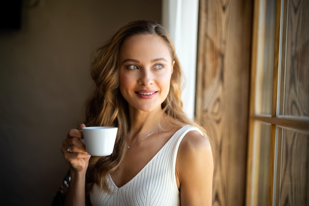 Heureuse jeune femme avec une tasse de café à la maison
