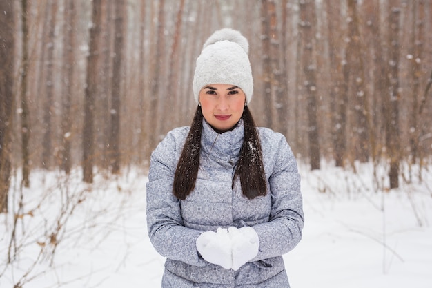 Heureuse jeune femme tenant la neige dans le parc d'hiver