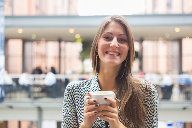 Heureuse jeune femme tenant une tasse de café