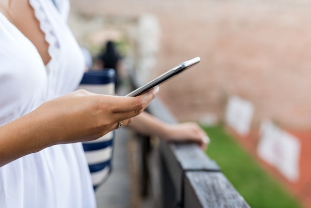 Heureuse jeune femme textos sms à l&#39;extérieur.