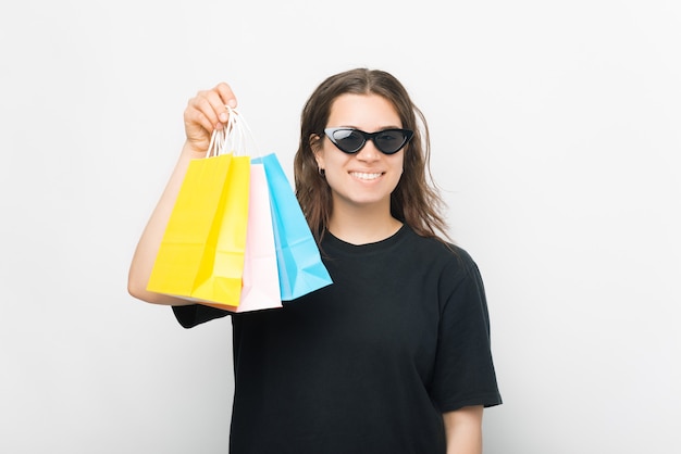 Heureuse jeune femme tient des sacs à provisions sur fond blanc.