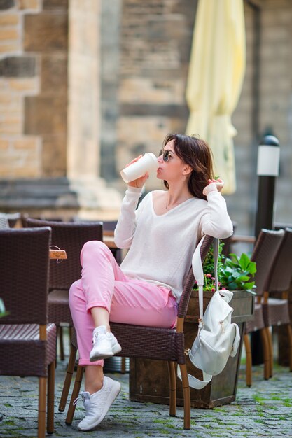 Heureuse jeune femme urbaine, boire du café en Europe. Caucasien touristique profiter de ses vacances en Europe dans la ville vide