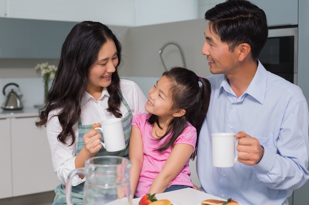 Heureuse jeune fille appréciant le petit déjeuner avec les parents