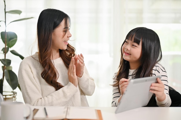 Heureuse jeune fille asiatique montrant son score au test via une tablette à sa mère