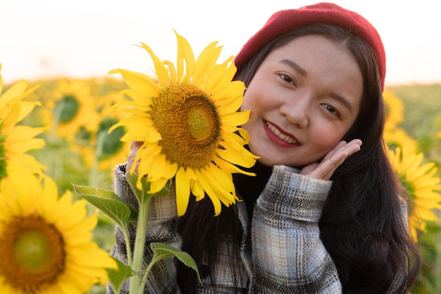 Heureuse jeune fille au champ de tournesols avec un ciel bleu