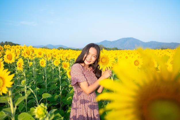 Heureuse jeune fille au champ de tournesols avec un ciel bleu