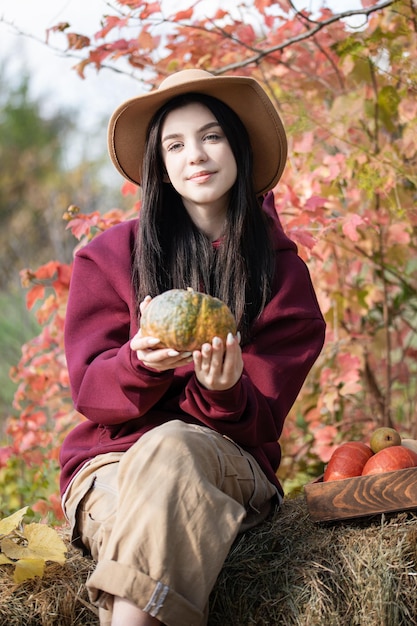 Heureuse jeune fille à la citrouille dans le jardin d'automne