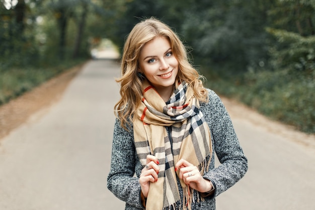 Heureuse jeune fille dans un manteau et une écharpe vintage en automne parc